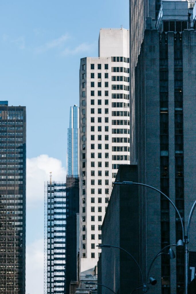 Facades of tall gray buildings on sunny street of megapolis